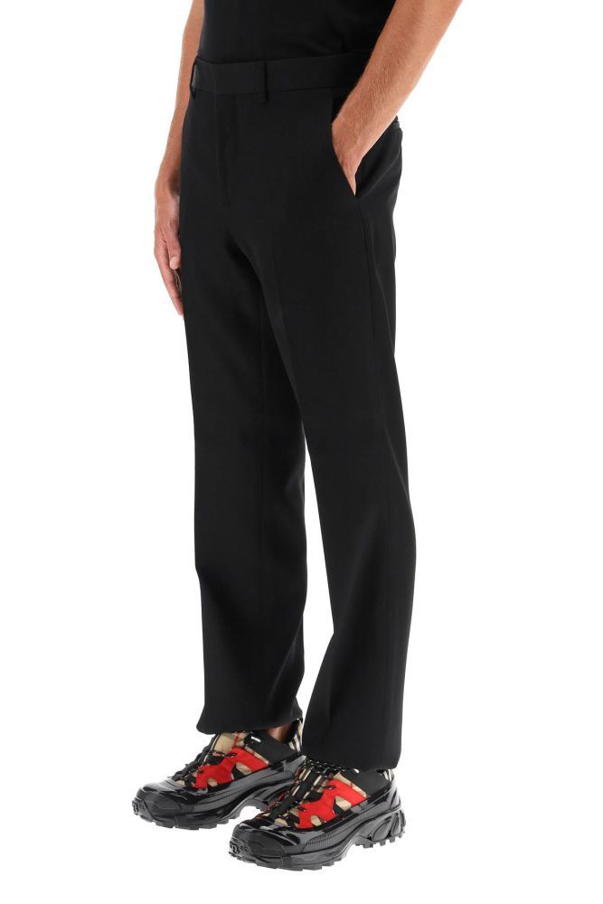 Classic-cut tailored trousers by Burberry in wool canvas, featuring a straight leg cut with flat front and ironed crease. Medium waist, concealed hook and zip closure. Side French pockets, rear welt pockets with button. The model is 185 cm tall and wears a size IT 48.