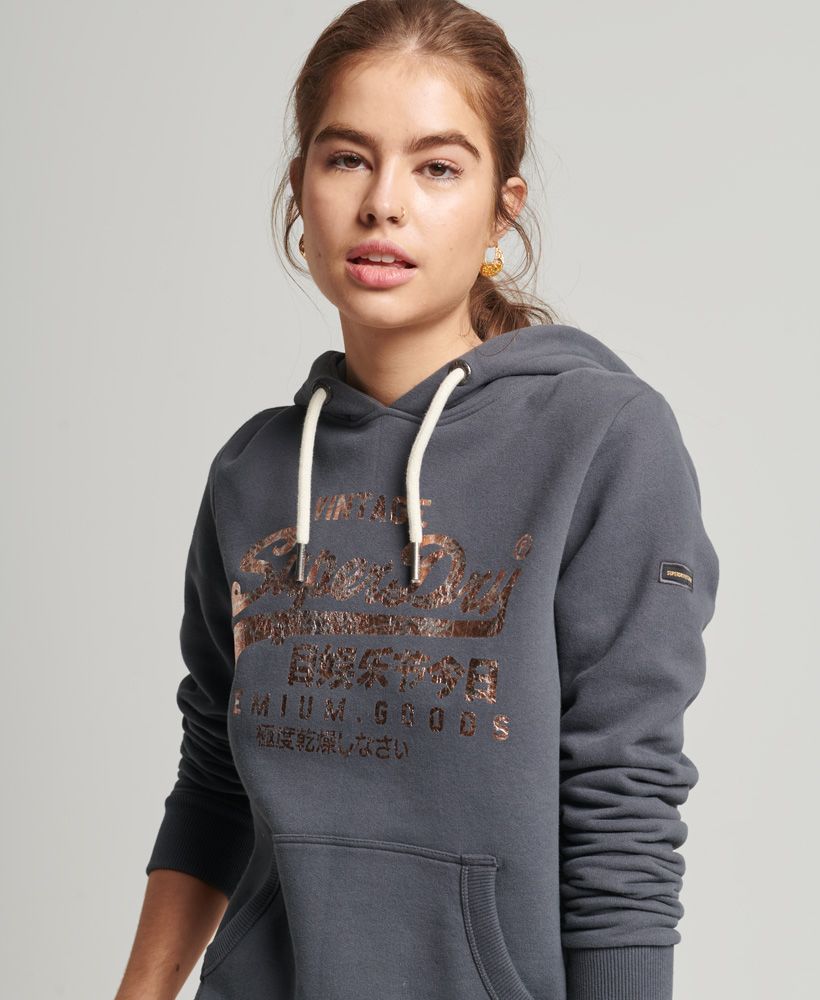 Our Vintage logo is part of our heritage and it's become iconic. Become part of that history with the Vintage Logo Tonal hoodie. The classic hoodie design that lives in so many wardrobes is paired with a crushed effect foil print logo that elevates this staple.Relaxed fit – the classic Superdry fit. Not too slim, not too loose, just right. Go for your normal sizeDrawcord hoodFront pouch pocketRibbed cuffs and hemSleeve logo patchFoil printed logoBrushed lining