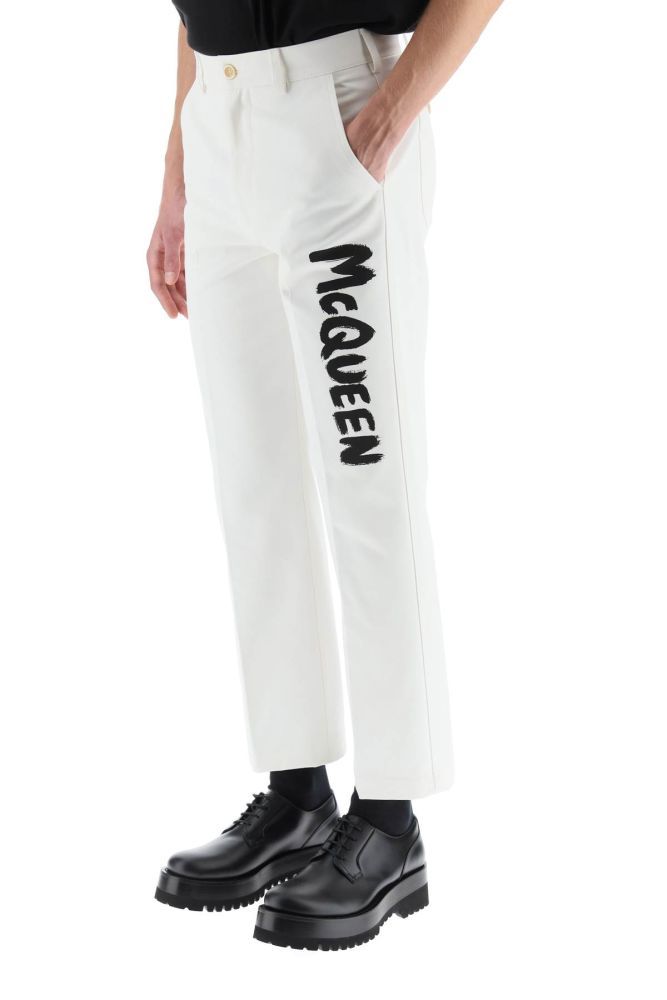 Alexander McQueen informal trousers in white cotton gabardine with McQueen Graffiti logo printed along the leg. Loose straight leg cut, featuring rear patch pockets with horn button, zip fly and button fastening, front slash pockets. Side patch pocket. The model is 185 cm tall and wears a size IT 46.
