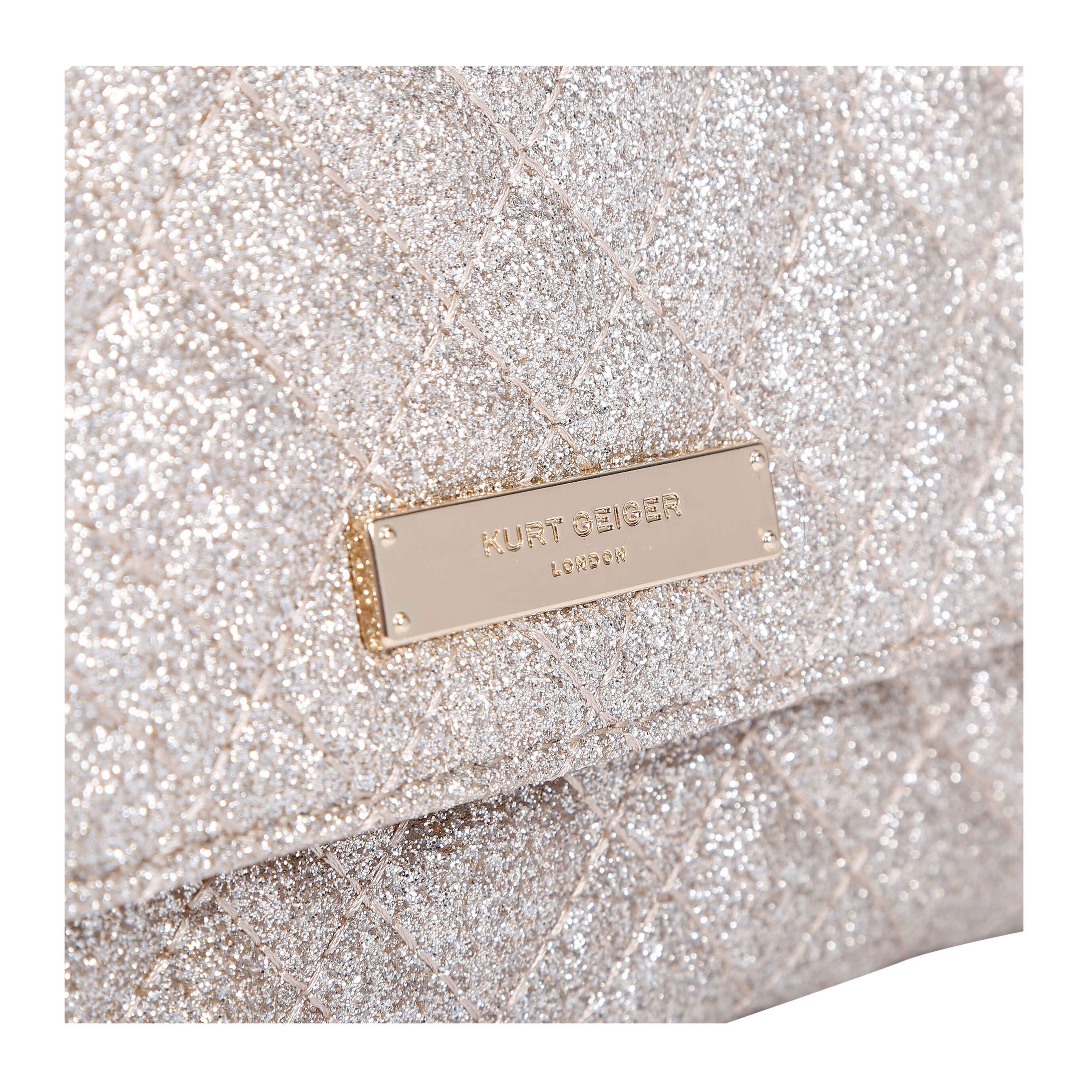 The gold Brixton Chain Wallet is crafted from glitter fabric with overstitch quilting design. There is a gold tone metal branded plate on the front flap.