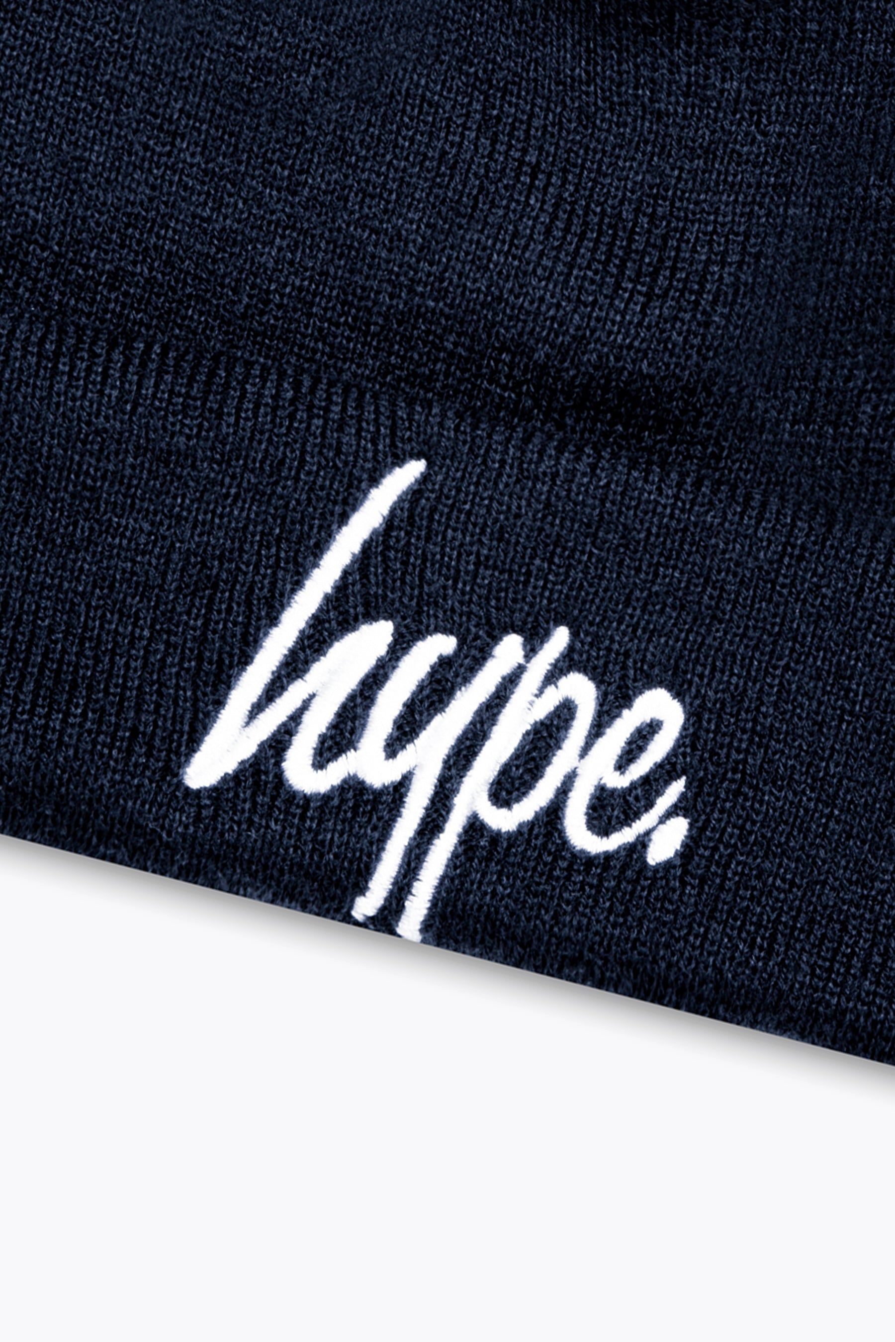Stay cosy in the HYPE. Navy Script Kids Beanie. Designed in an all-over navy colour palette. With a soft-touch woven acrylic fabric for supreme comfort. In our classic junior's beanie shape with a turned-up cuff design, finished with the iconic HYPE. script logo embroidered on the front in a contrasting white. Machine washable.