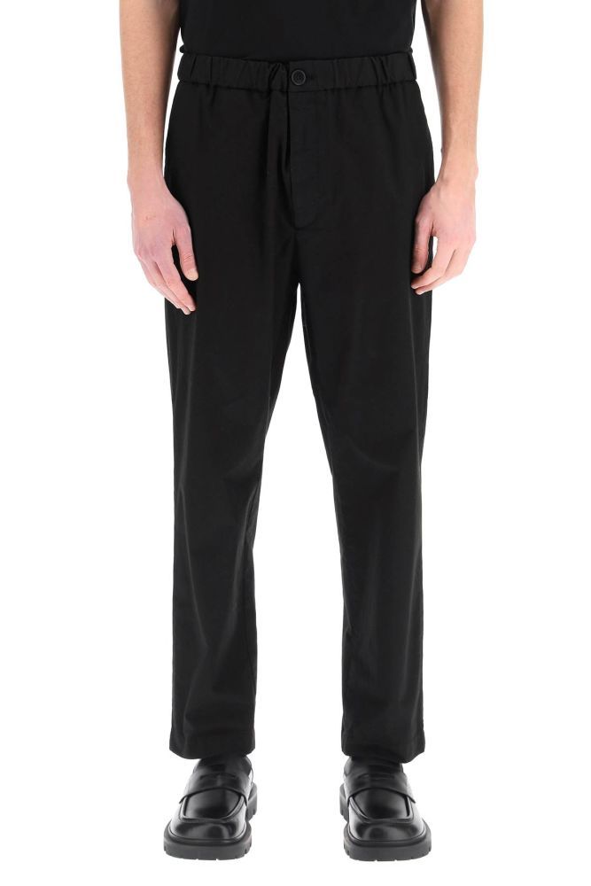 Jil Sander+ casual trousers in lightweight cotton featuring a relaxed fit and a tapered leg cut with elasticated waistband. Closure with horn button and zip fly, side seam pockets, rear patch pockets. Logo loop on the back waist. The model is 187 cm tall and wears a size IT 46.