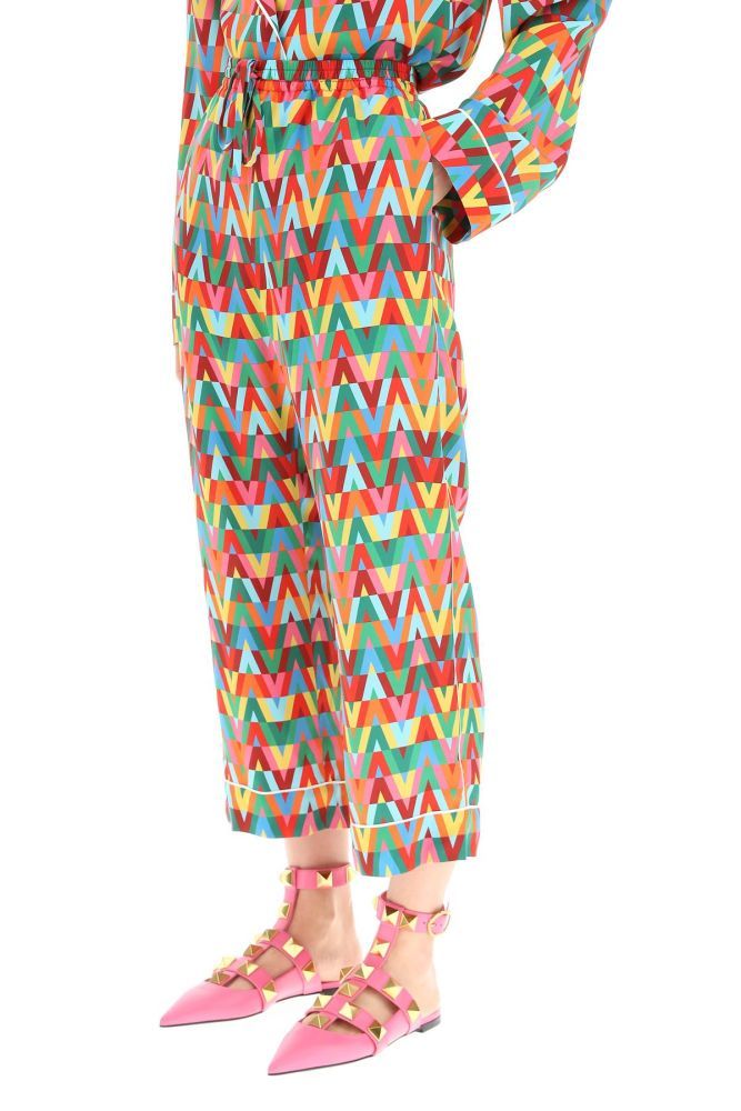 Valentino pajama pants crafted in Crepe de Chine with all over V Optical Valentino Archive 1973 print. Contrasting piping, side french pockets, rear welt pockets, stitched cuffs, elasticated waistband with drawstring. Relaxed fit, ankle-length. The model is 177 cm tall and wears a size IT 40. 