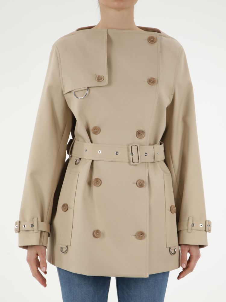 Short beige cotton raincoat with double-breasted closure. It features front buttons, adjustable belt on waist, two side buttoned welt pockets, adjustable buckle on cuffs and back slit.The model is 178cm tall and wears size 6.