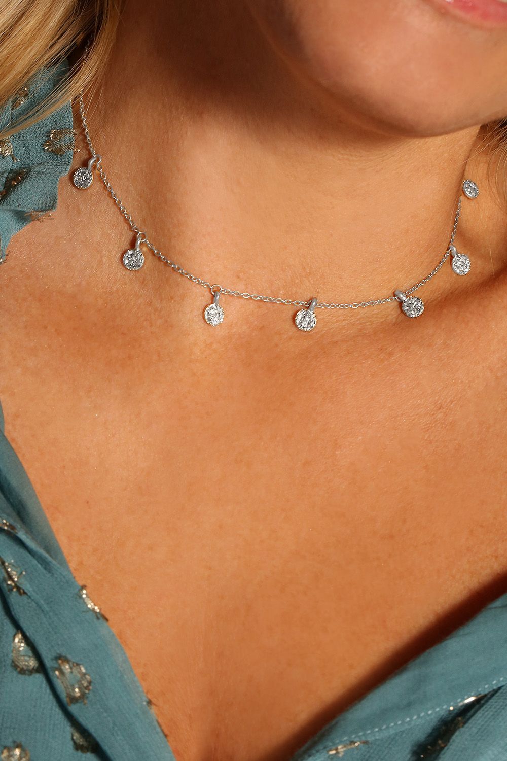 If you love your boho jewellery, this one's for you. It features a dainty silver choker with miniature coins that dance across your neck! The silver plated necklace features hammered silver detailing and looks amazing layered with another longer necklace with a low neckline outfit, or over the top of a jumper during the day! It measures 15 inches and comes with a lobster clasp fastening and a 3 inch extender. The Boho choker necklace is designed as a classic piece that you can wear with so many looks!