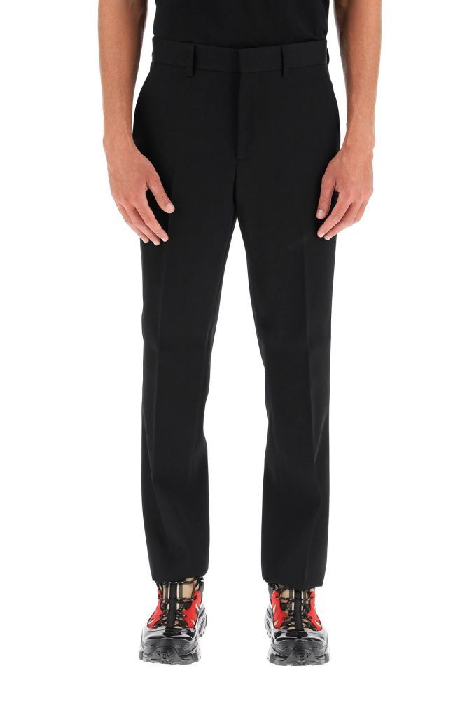 Classic-cut tailored trousers by Burberry in wool canvas, featuring a straight leg cut with flat front and ironed crease. Medium waist, concealed hook and zip closure. Side French pockets, rear welt pockets with button. The model is 185 cm tall and wears a size IT 48.