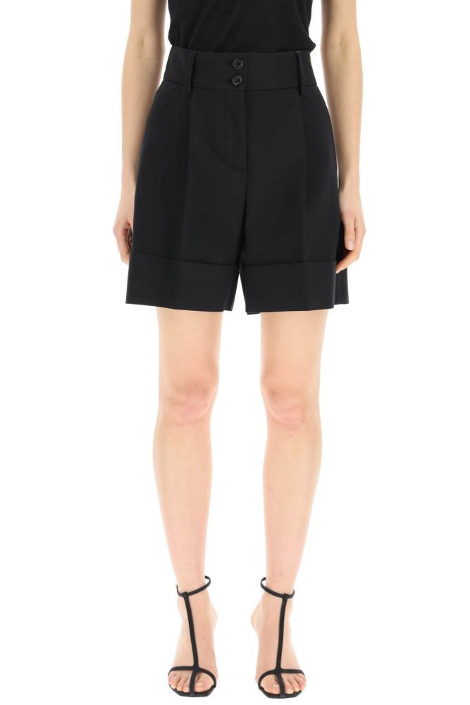 See By Chloé high-waisted tailored shorts in cotton blend fabric with front pleats and cuffed hem. Zip fly and buttons, side pockets, two rear welt pockets. The model is 177 cm tall and wears a size FR 36.