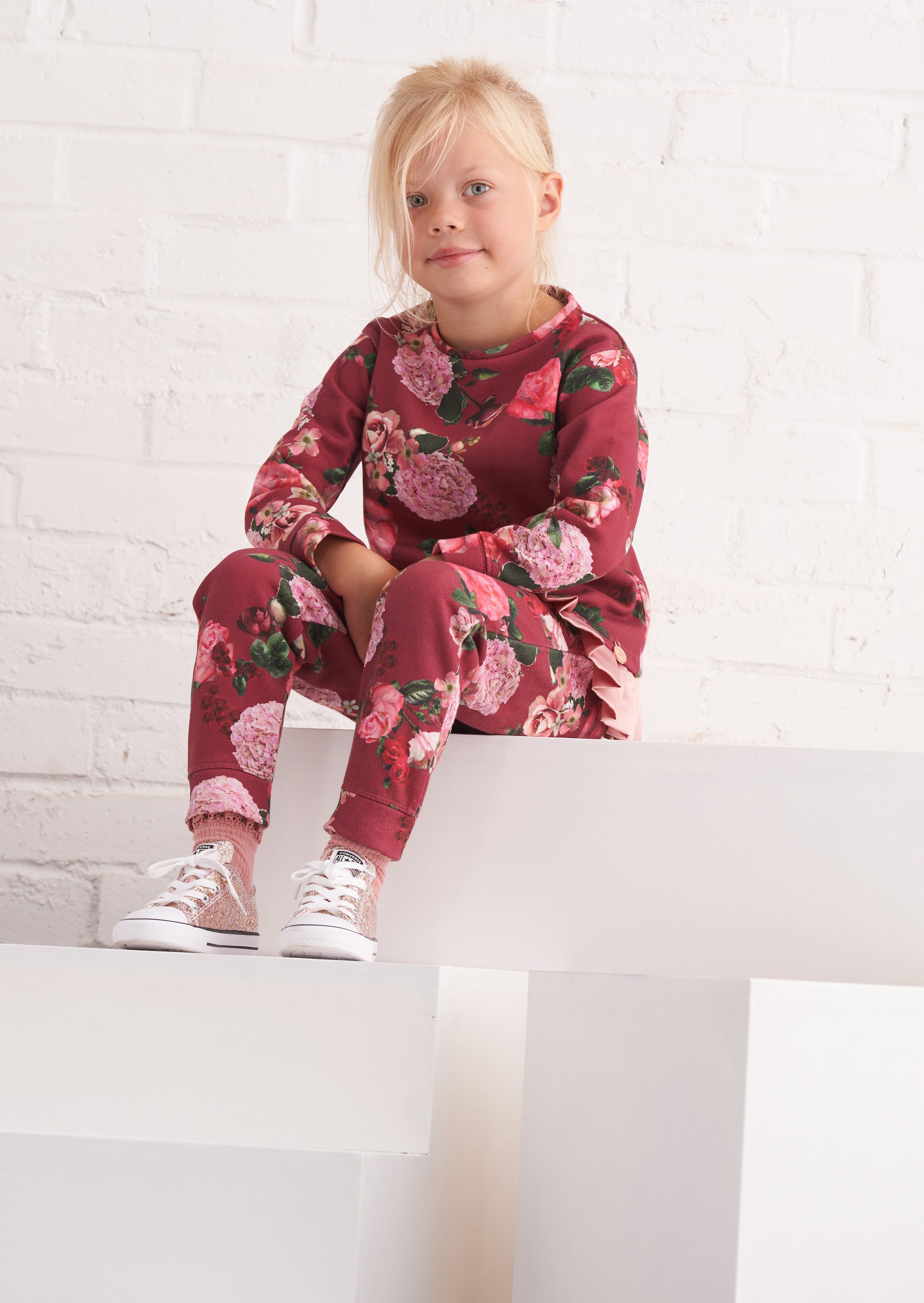 Opt for fun florals with these super cute joggers. Beautiful blooms printed on a super soft loopback with a satin bow and elasticated waist. Wear with the matching sweat and trainers for a cute co-ord. > Angel & Rocket cares – made with fairtrade cotton > Colour: Ruby red > About me: 80% cotton 20% polyester  > Look after me – Think planet > Wash at 30c