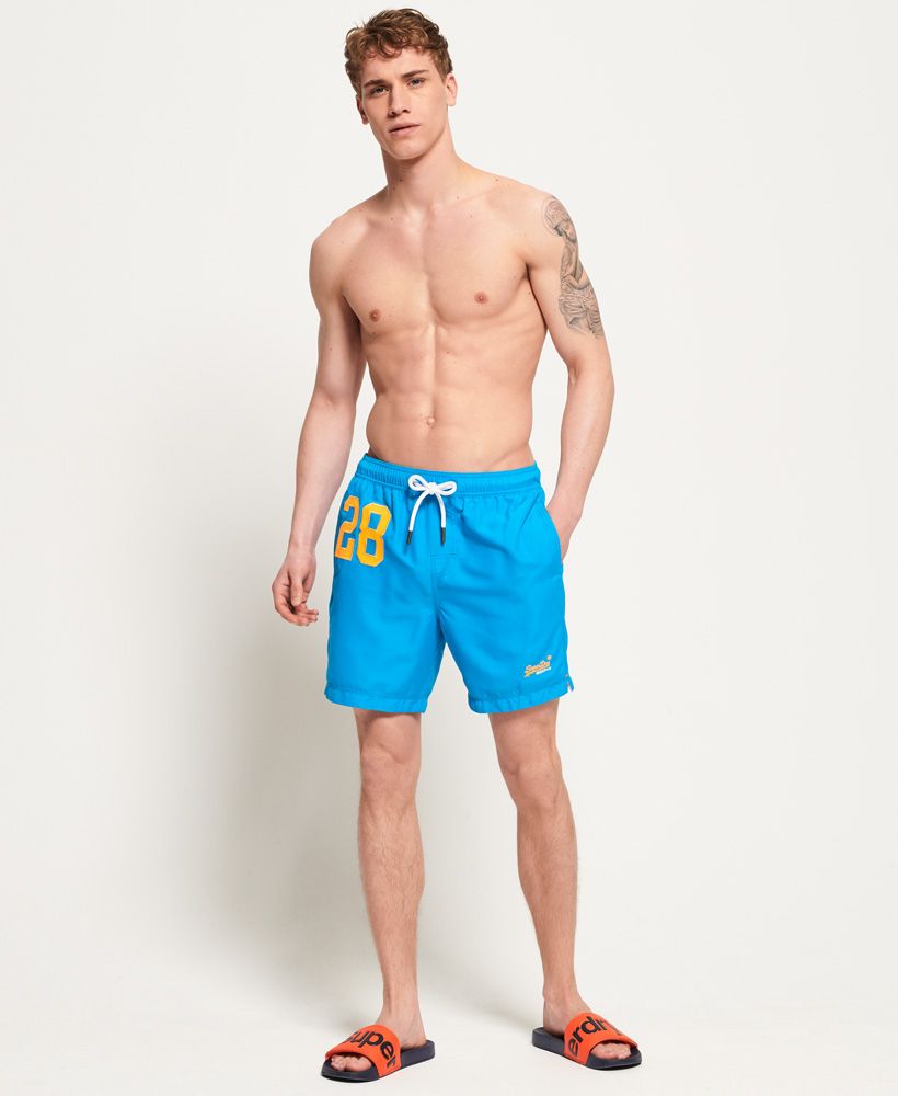 Superdry men’s Waterpolo swim shorts. A pair of swim shorts featuring an applique print on one leg and a two colour embroidered Superdry logo above the leg opening. The swim shorts come with two front pockets and one zip pocket on the back. The Waterpolo swim shorts also have an elasticated waistband with a drawstring fastening, signature orange stitching accents and are finished with an inner mesh lining for added comfort.