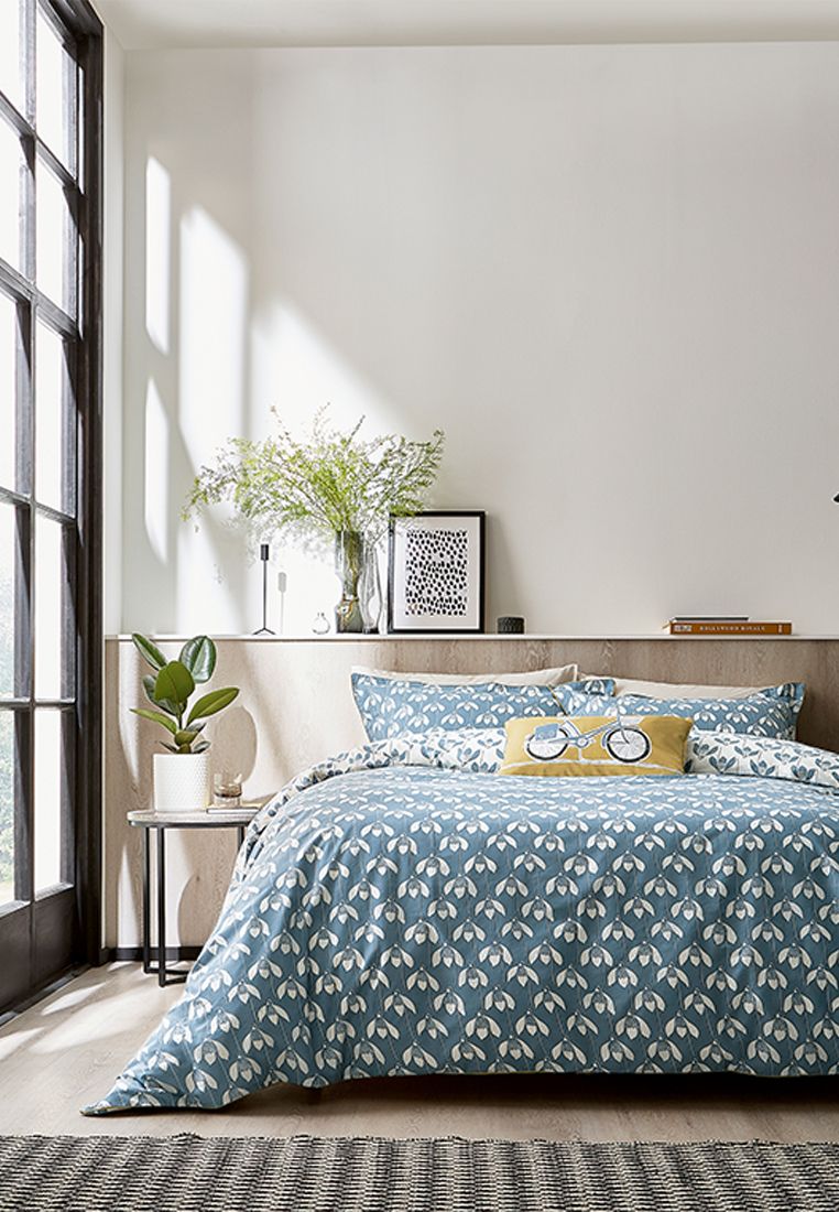 Snowdrop features an all-over stylised flower head set against a light blue ground. The design is reflected in a contrasting colourway on the reverse and finished with a grey piped edging. Printed on pure cotton, Snowdrop is available in four sizes of duvet cover sets which include a matching Oxford pillowcase(s). A textured cotton cushion featuring a bicycle print adds a quirky finishing touch. Fibre Filled, Made in Pakistan.