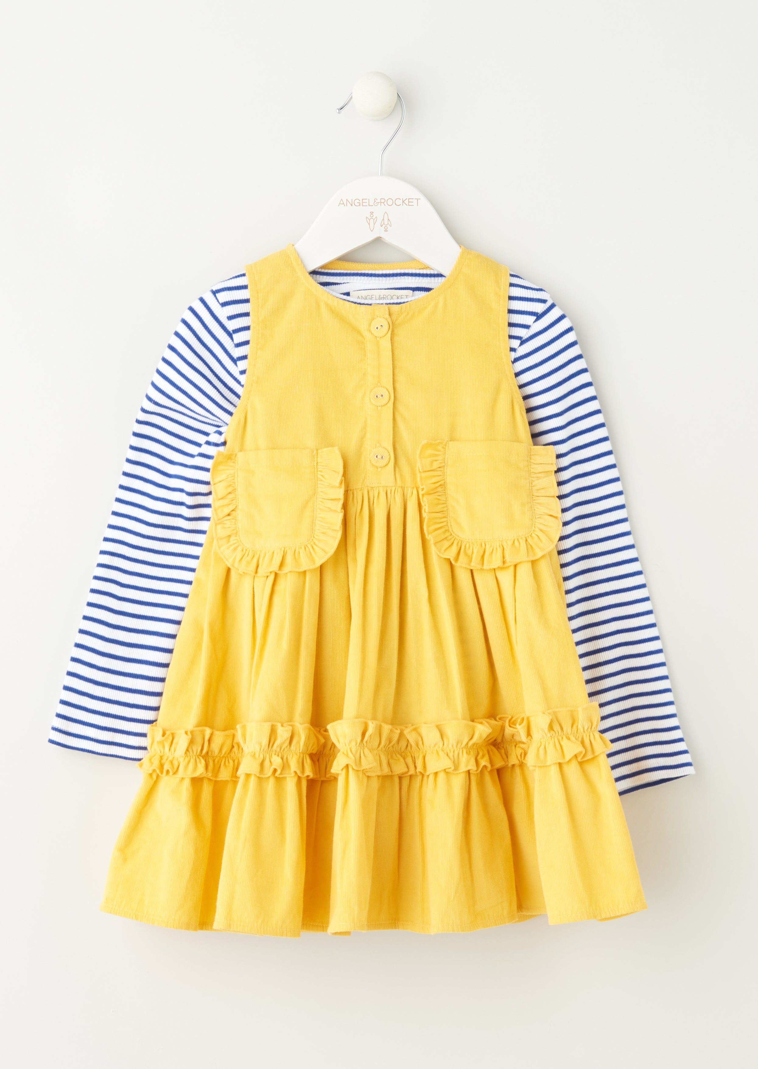 Be bold in ochre! Our tiered cord pinny is a must have. In a super soft baby cord with playful ruffles patch pockets and covered buttons. Teamed with breton navy and white stripe skinny rib long sleeve top. It's perfect for playtime! > Angel & Rocket cares – made with fairtrade cotton > Colour: Ochre > About me: 95% cotton 5% metallic yarn > Look after me – Think planet > Wash at 30c