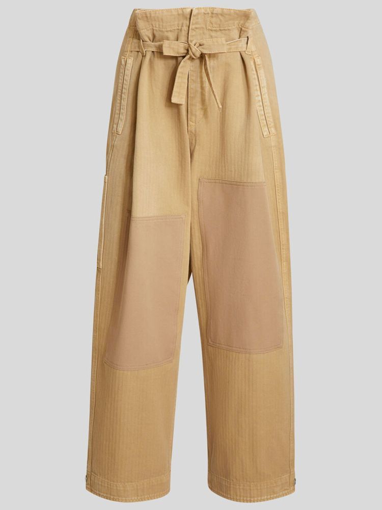 Beige cotton paperbag culottes with tucks. It features patchwork details, waist belt, button and zip fastening, two side welt pockets, one rear welt pocket, one rear patch pocket and press buttons at the bottom. The model is 178cm tall and wears size 40.