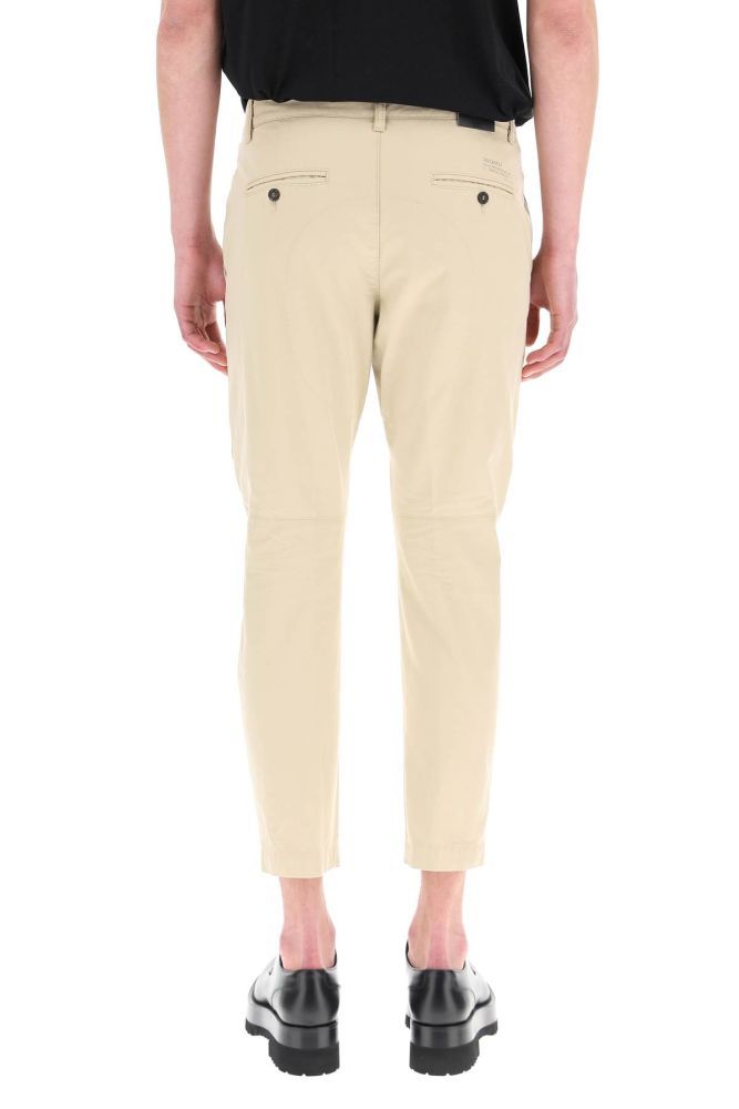 Cotton gabardine pants by Dsquared2, featuring a mid-rise slim fit with long crotch and cropped length. Button fly, side slanted pockets, rear button-through bound pockets, reinforced crotch, ergonomic curvature at the knees. Logo detail printed on the back. The model is 187 cm tall and wears a size IT 48.