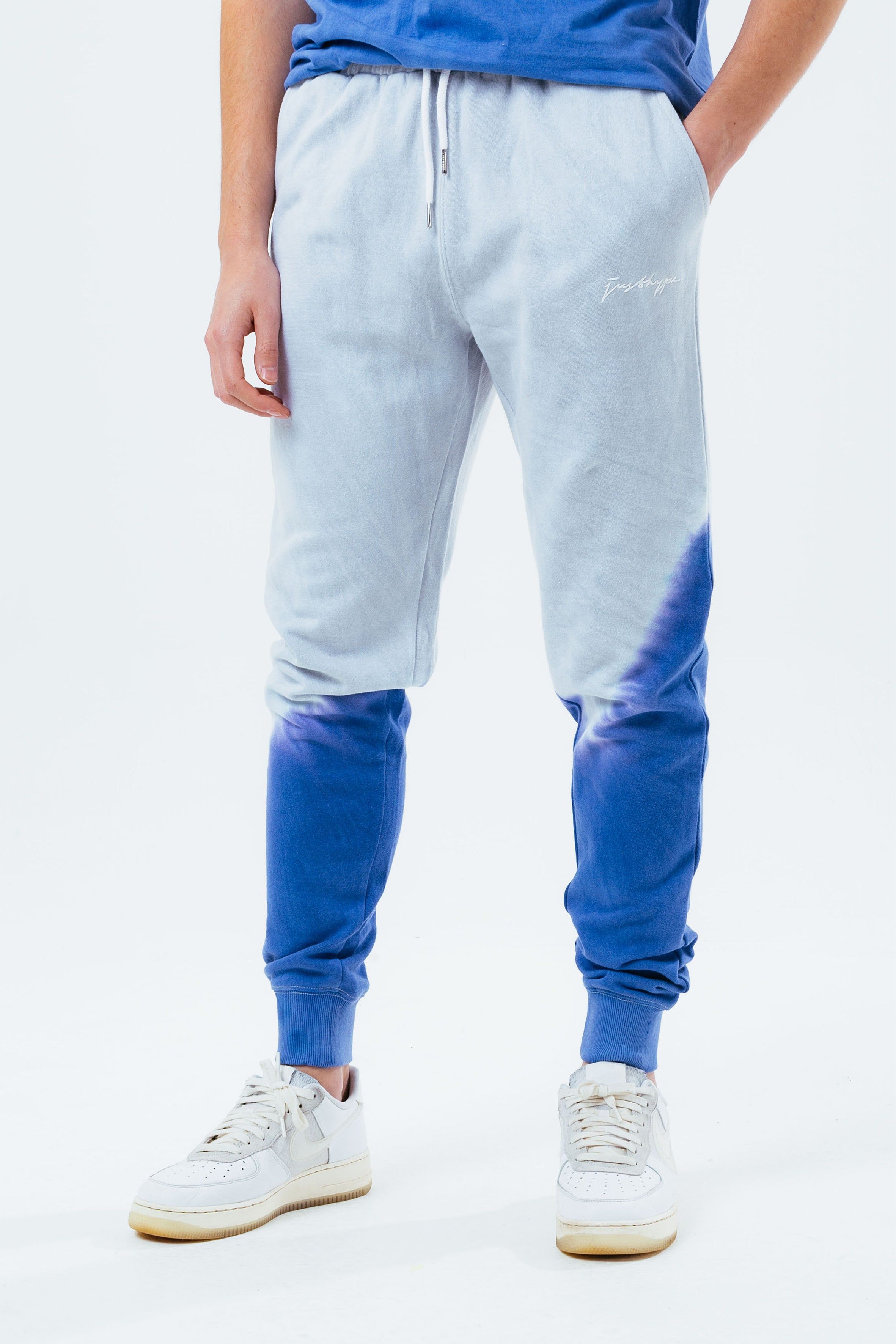 Stay on trend with the Hype Grey Navy Tie Dye Scribble Logo Men's Joggers and grab the matching hoodie to complete the set. Designed in a soft-touch 70% Cotton 30% Polyester fabric base with the supreme amount of comfort you need from your new joggers. The design boasts an acid wash or tie-dye wash finish with an elasticated waistband, drawstring pullers and fitted cuffs. Machine wash at 30 degrees.