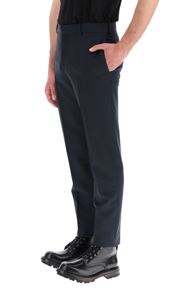 Alexander McQueen tailored trousers in lightweight wool and mohair fabric featuring a cigaret cut with ironed crease. They feature concealed zip and hook closure, side slit pockets, jetted back pockets with button, belt loops, back vent. They come unhemmed to allow further tailoring. The model is 183 cm tall and wears a size IT 46.