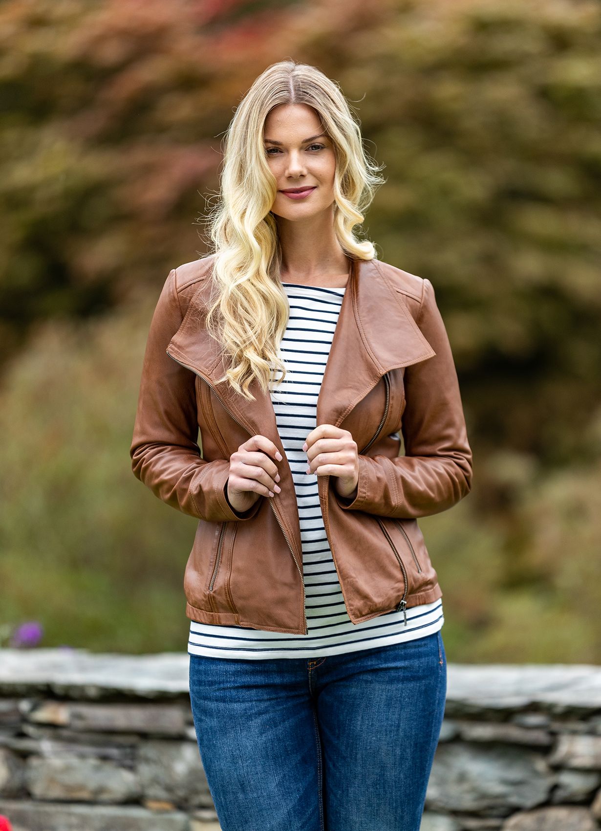 Inject instant style into your wardrobe with our Jill leather biker jacket in tan. The Jill is a style that returns year after year in new colourways. It's a best-selling style for a reason. The casual cut and slightly longer length accommodates all shapes and sizes. The larger collar is incredibly flattering with subtle design features that create the perfect casual biker jacket look.  Expertly crafted from soft and supple aniline leather, Jill is practical as well as stylish. The ever on-trend biker jacket features definitive details such as an asymmetric zip and two zip pockets with brushed metallic detailing.