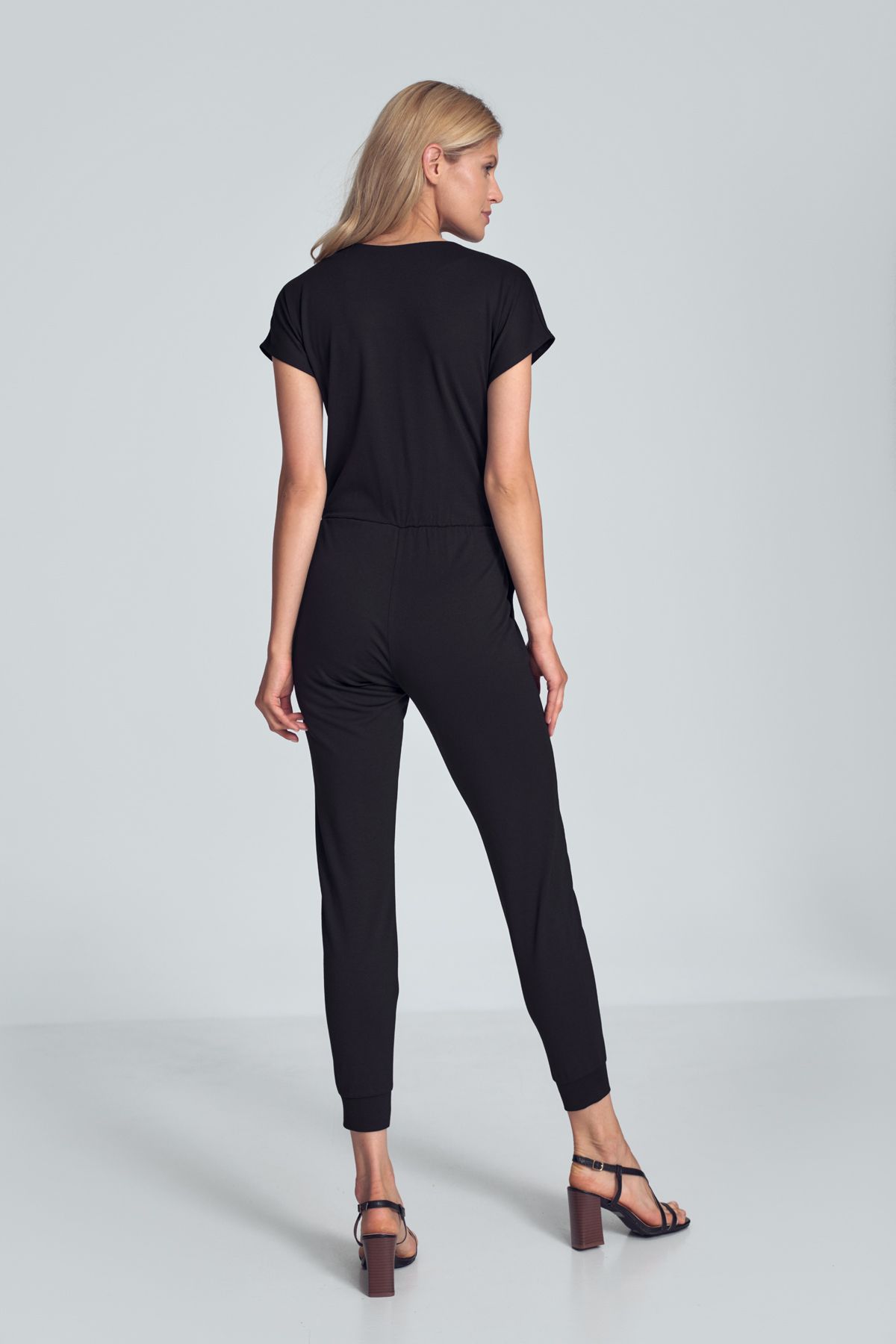 Black jumpsuit with a sporty cut, wrinkled neckline, an elastic band sewn at the waist, narrow legs finished with a welt. Pockets in the side seams.
