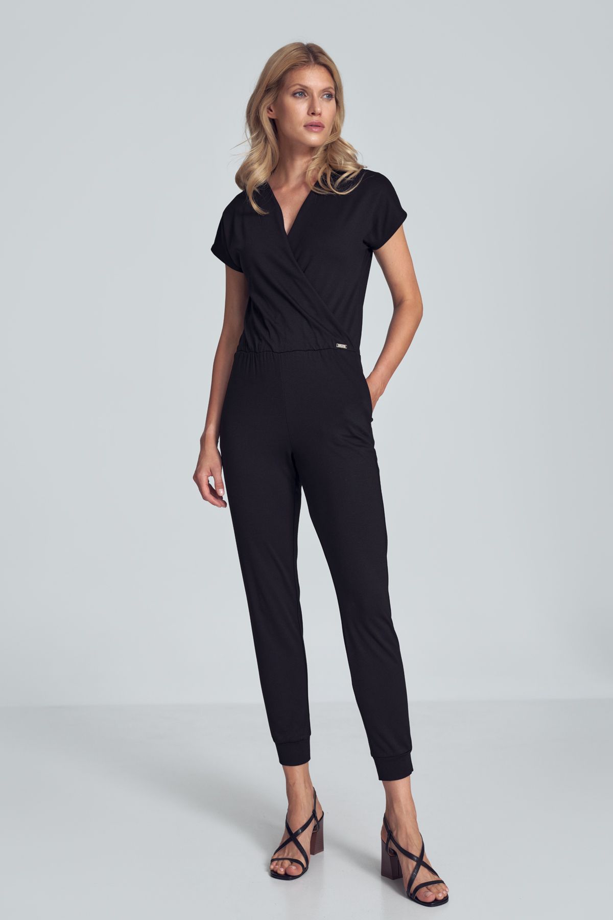 Black jumpsuit with a sporty cut, wrinkled neckline, an elastic band sewn at the waist, narrow legs finished with a welt. Pockets in the side seams.