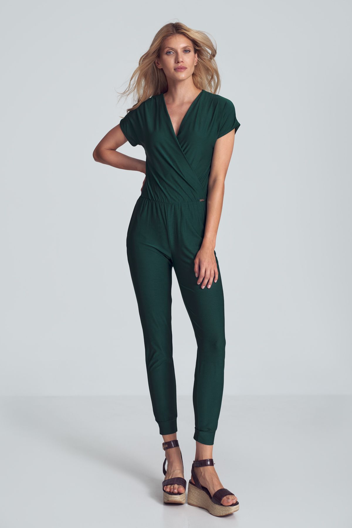 Zielony jumpsuit with a sporty cut, wrinkled neckline, an elastic band sewn at the waist, narrow legs finished with a welt. Pockets in the side seams.