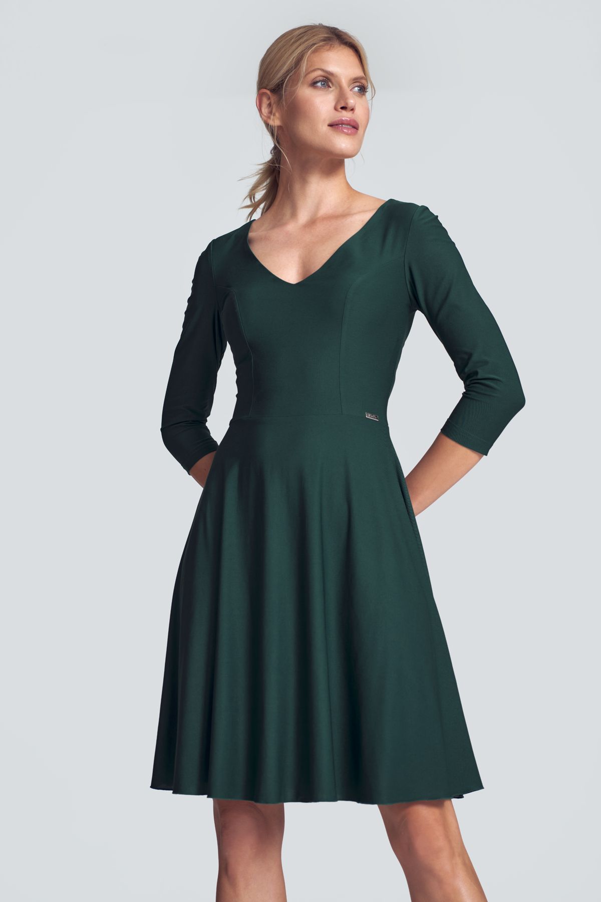 Green cocktail midi dress with a V-neck, ¾ sleeve, pleats at the bust, sewn at the waist, flared hem. Fastened at the back with a covered zipp.