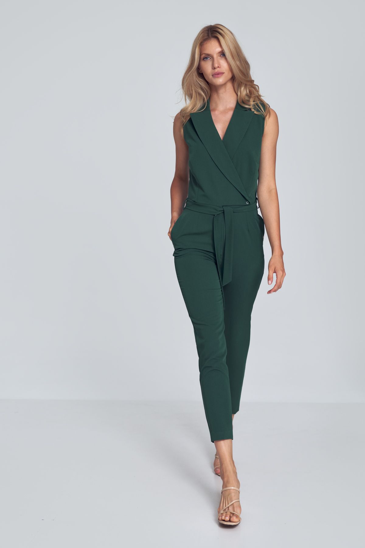 Green V-neck jumpsuit with a collar, sleeveless, tied at the waist, loose legs tapered to the bottom. Fastened at the front at the waist with one external and internal snaps and a covered zipper. Pockets in the side seams.