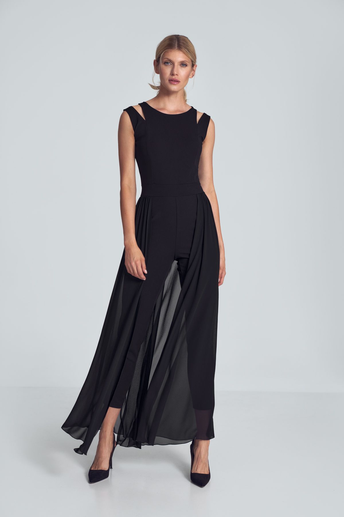 Black jumpsuit with long chiffon skirt slit at the back. Sleeveless, delicate decorative slits on the shoulders, a small semi-circular neckline. Heavily tapered legs. Fastened at the back with a covered long zipper.