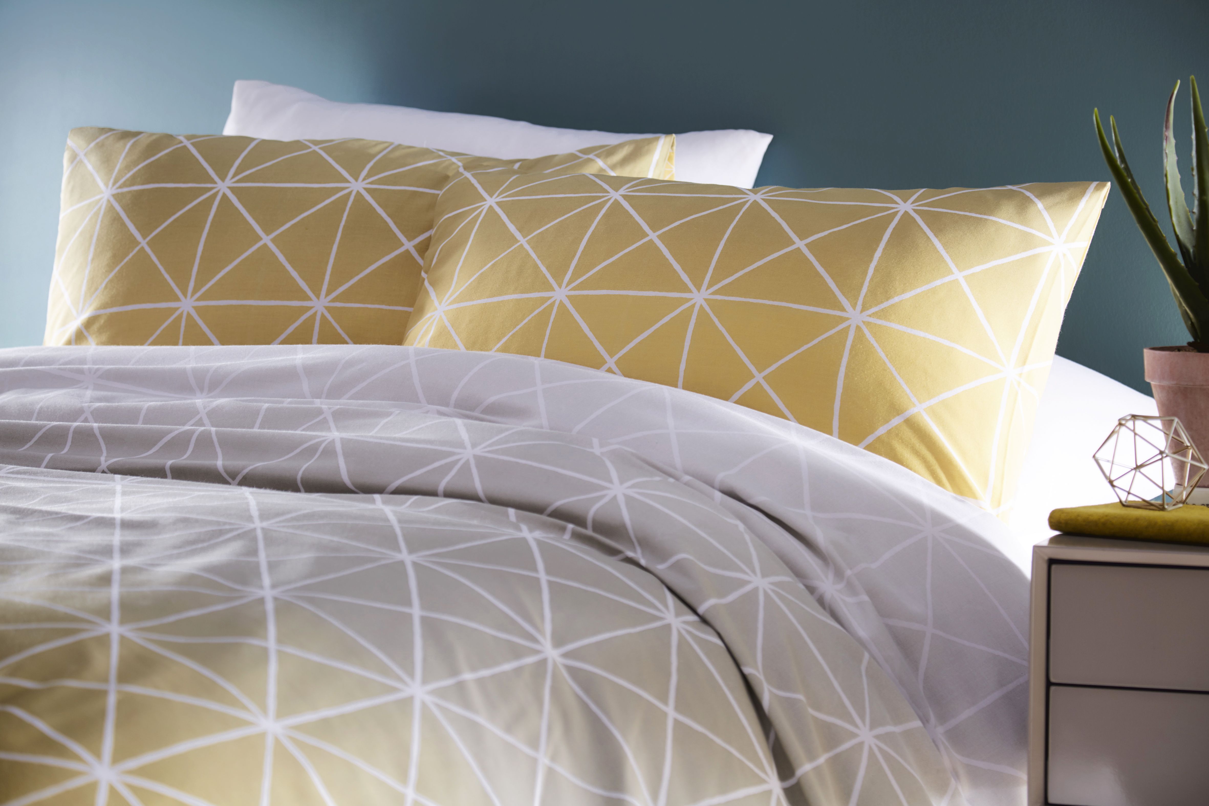Featuring a gorgeous gradient flowing from a crisp white, to Dove Grey and finishing on a beautiful Ochre the Spectrum duvet cover set is a versatile piece. Complete with thin white lines in a geometric pattern it brings a modern touch that will elevate your bedroom into a contemporary space. The reverse has a matching plain Ochre with white dots to neutralise the statement front. Each duvet set comes with matching pillowcases with a reversible design. Made of crisp polycotton making this duvet set soft and hard-wearing. This duvet cover features a secure button closure while the pillowcases have an envelope closure. Machine washable on a 40 degree cycle. Iron cool and tumble dry on a low setting for the best finish.
