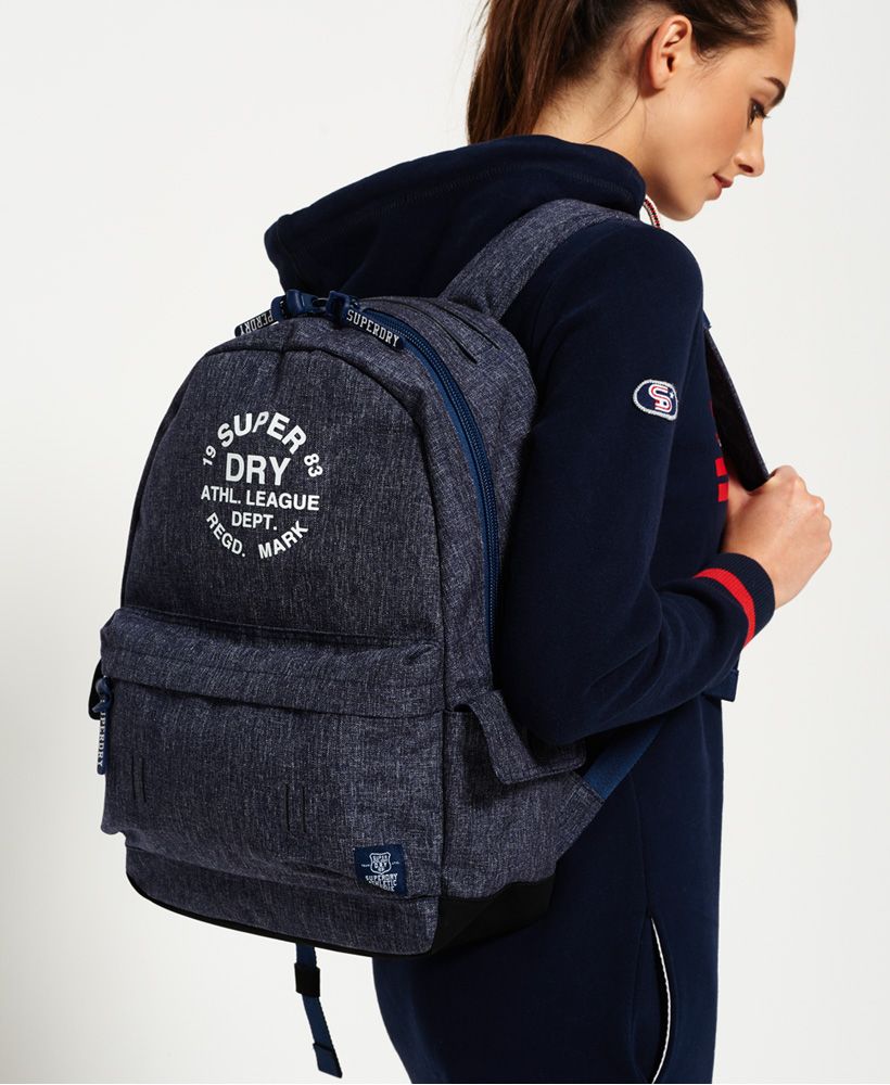 Superdry women’s Athletic League Montana rucksack. A rucksack with a top grab handle, padded back and straps and a large main compartment. The Athletic League rucksack features twin side pockets with popper fastening and a zipped outer compartment and is finished with branded zip pulls and a Superdry Athletic League print on the front and logo patch on the front pocket. 
17 litre approximate capacity 
H 45cm x L 30cm x D 13cm.