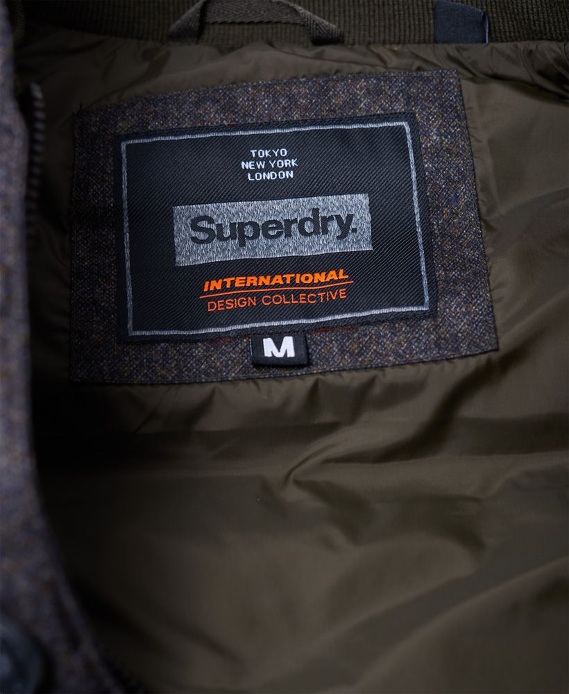 Superdry men's Tech Tweed gilet. Perfect for that heritage look, the Tech Tweed gilet is a classic quilted gilet with a mottled tweed effect shoulder panel. The gilet fastens with a zip, button and popper fastening and has two zipped pockets and a patch chest pocket. Inside there is a small ribbed inner collar and a single pocket with a popper fastener. The Tech Tweed gilet is finished with a Superdry logo patch above the hem.Model wears: Medium Model height: 6’ 1” (185cm) Model chest size: 39