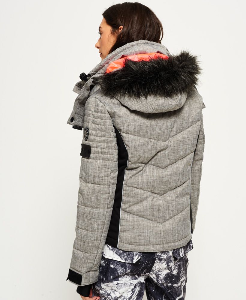 Superdry women’s snow puffer jacket. The snow puffer jacket features a hood with a detachable faux fur trim as well as bungee cord adjusters. This snow jacket benefits from a total of three external zip pockets, including one on the left sleeve, and an internal pocket with a removable cloth for ski goggles. This jacket also has earphone cable routing, removable lining with thumbholes on the cuffs as well as a hook and loop fastening, a removable snow skirt and a bungee cord fastening on the hem. This ski jacket is finished off with Superdry branding on the zips, Superdry logo branding on the cuffs, and two Superdry logo badges on the sleeve. 

Model wears: Small Model height: 5' 10