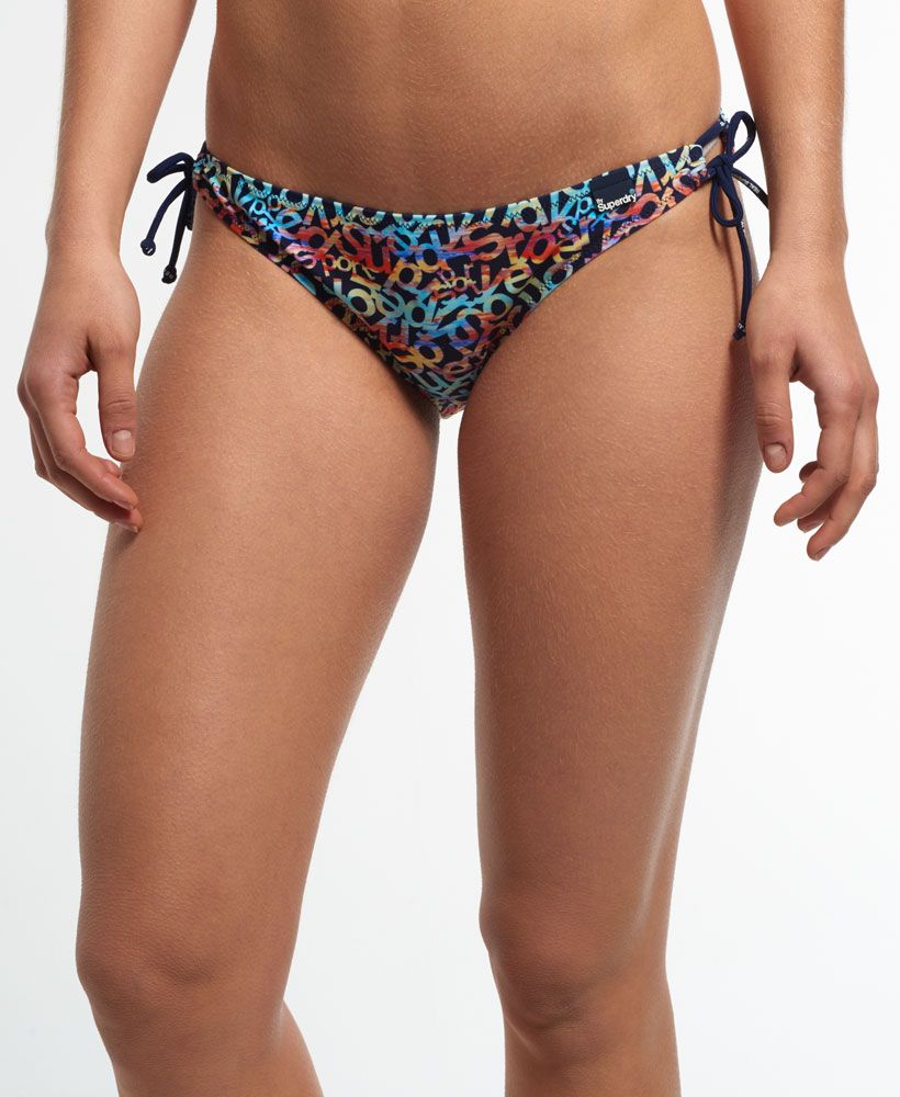 Superdry women's Sunset bikini bottoms. A pair of classic bikini bottoms featuring an all over multi coloured Superdry design with spaghetti strap side ties and a subtle By Superdry logo tab on the waistline.
 Please note due to hygiene reasons, we are unable to offer an exchange or refund on swimwear unless they are sealed in their original packaging. This does not affect your statutory rights.Model wears: Small Model height: 5’9” (175cm)