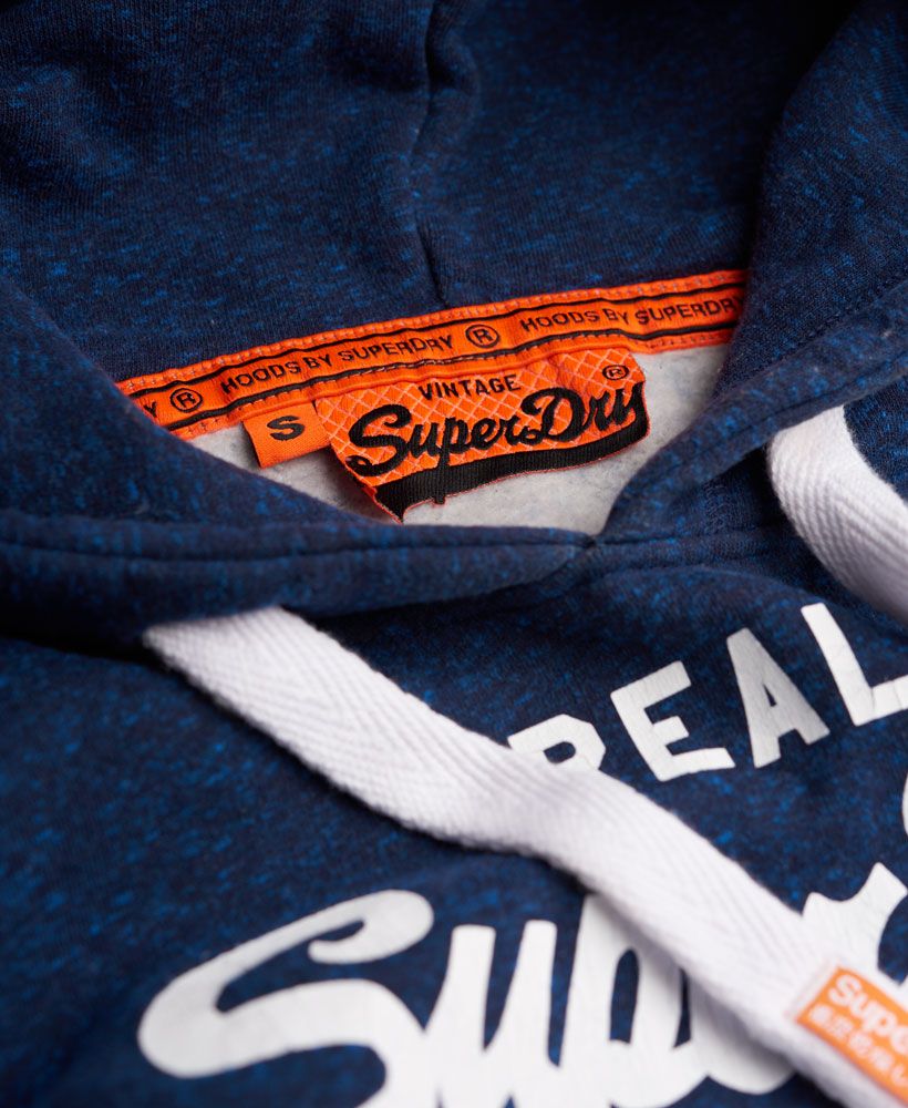 Superdry women's Vintage Logo Hoodie. An over-the-head style hoodie featuring a cracked print version of the iconic Real Superdry logo across the chest, a front pouch pocket and a drawstring hood. The hoodie is finished with a Vintage Superdry logo tab on the cuff and a signature orange stitch in the side seam.Model wears: Small Model height: 5’ 10” (178cm)