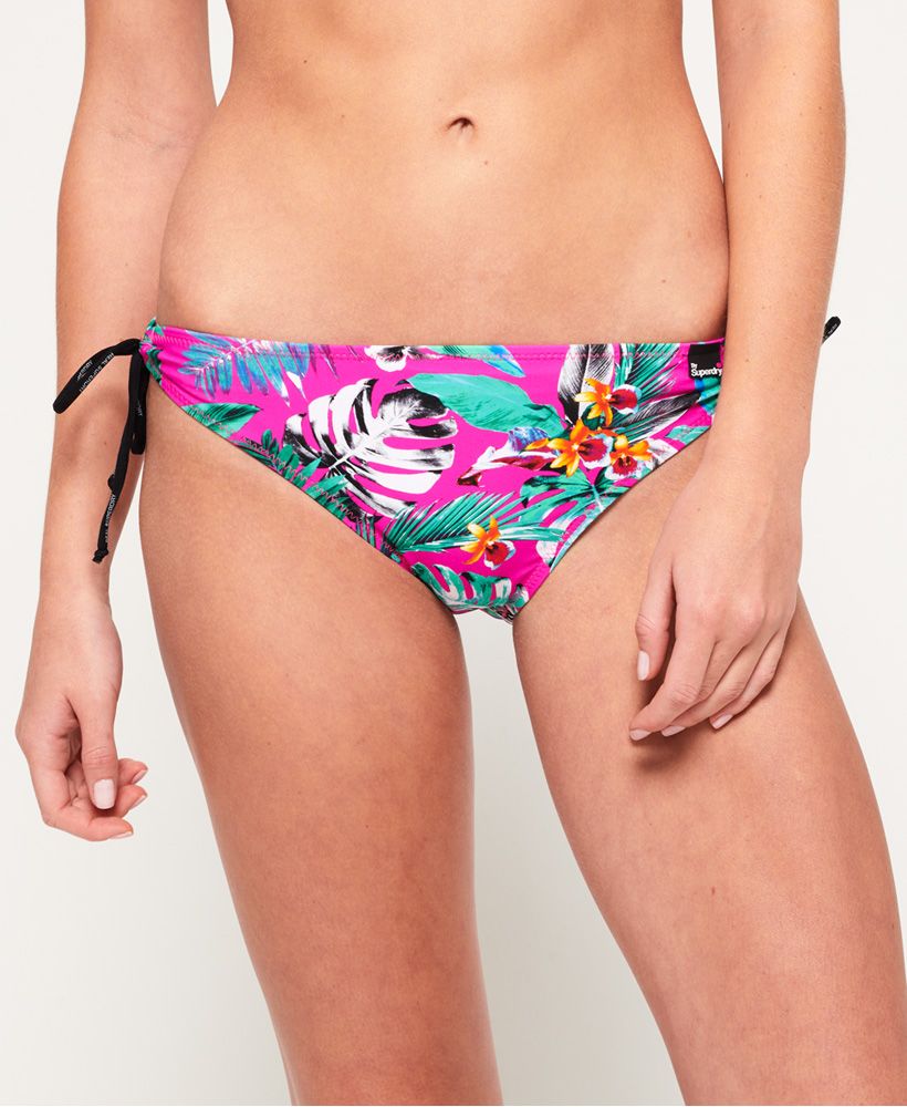 Superdry women’s Electro Tropic tie bikini bottoms. These bikini bottoms feature branded, spaghetti strap hip fastenings on both sides and are finished with a rubber Superdry logo tab on the front.Model wears: 10/Small Model height: 5’11” (180cm) Please note due to hygiene reasons, we are unable to offer an exchange or refund on swimwear, unless they are sealed in their original packaging. This does not affect your statutory rights.