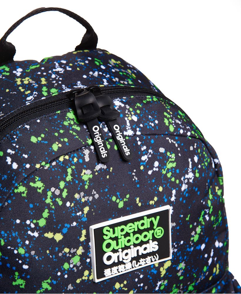 Superdry men’s splatter Montana rucksack. The classic Montana rucksack features an all over splatter print, a top grab handle, padded back and straps for extra comfort and a large main compartment. The mini Splatter Montana also features twin side pockets with popper fastening, a front zipped compartment and a silicone Superdry Outdoor Originals logo patch and silicone branded zip pulls.21 litre approximate main compartment capacity.H 46cm x W 30.5cm x D 13.5cm