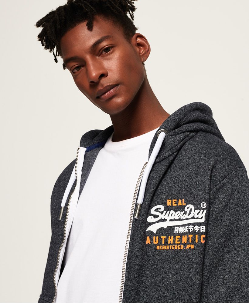 Superdry men’s Vintage Authentic Duo zip hoodie. This zip up hoodie features a drawcord adjustable hood, two front pockets and a rubberised Superdry logo on the sleeve. The Vintage Authentic Duo zip hoodie also features ribbed cuffs and hem and a rubberised Superdry logo design on the chest. The zip up hoodie is finished with a signature orange stitch in the side seam.
