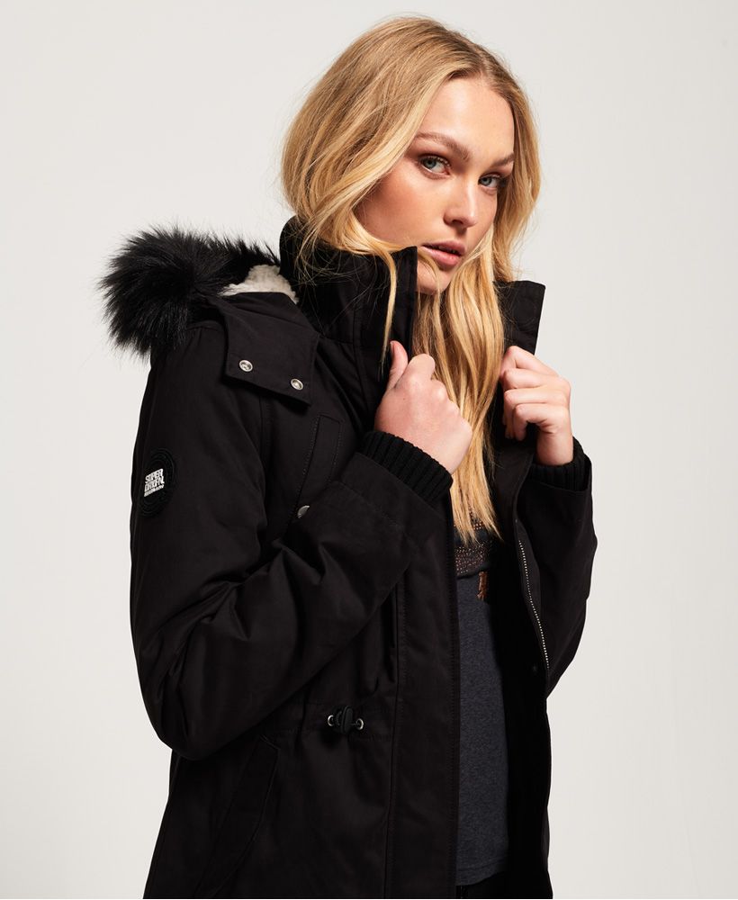 Superdry women’s Model microfibre faux fur jacket. This longer length jacket features a fleece lined hood with a detachable faux fur trim, a ribbed inner collar and a part fleece lining. This jacket also has ribbed cuffs, a bungee cord waistband, four front popper fastened pockets and a zip and popper front fastening. The jacket is finished with a metal Superdry logo badge on one pocket and a rubber Superdry International logo badge on one sleeve.