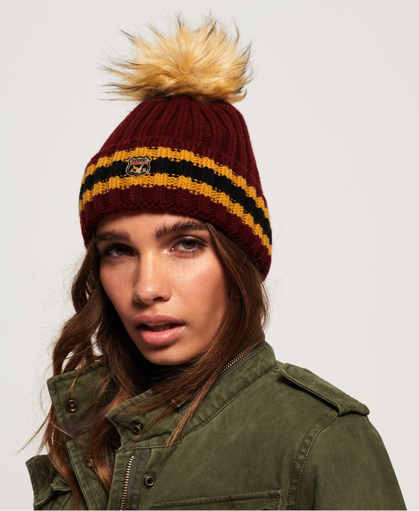 Superdry women’s Aimee striped ribbed beanie. Stay cosy and warm this season in this Aimee beanie. The ribbed knit design of the beanie allows the hat to shape perfectly to your head, creating a comfortable fit so you can wear this beanie all day. The Aimee beanie also features a faux fur bobble to add a contrasting colour to the stylish stripe detailing. A Superdry badge has been added to the front for the finishing touch.