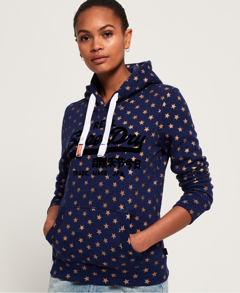 Superdry women’s Vintage Logo star all over print hoodie. Add to your hoodie collection this season with this overhead hoodie, featuring a drawcord adjustable hood, a large front pouch pocket and a textured Superdry logo graphic on the chest. Finished with a Superdry logo tab in the side seam, this hoodie will look great styled with boyfriend jeans and trainers. Slim fit