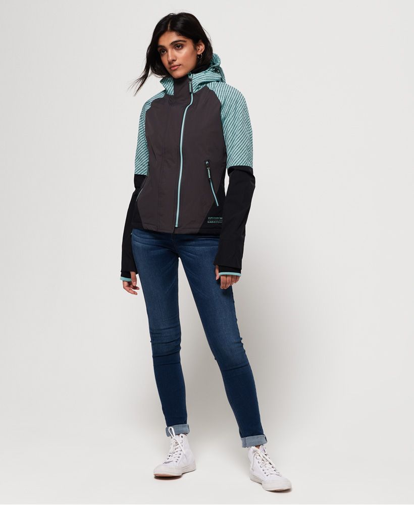 Superdry women's Arctic Impact SD-Windcheater. This lightweight jacket features a double layer zip fastening, fleece lined hood and body and two zipped front pockets. The jacket also features an inside pocket with a popper fastening and adjustable bungee cord hem. The Arctic Impact SD-Windcheater is finished with branded zip pulls, a logo badge on one sleeve and small logo design above the hem.