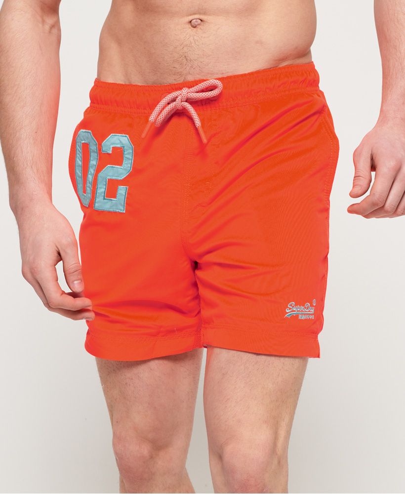 Superdry men's water polo swim shorts. Crafted from water reactivated fabric to show an all over print when wet, these swim shorts are a must have this season. Featuring a drawstring waistband, two front pockets and a back pocket with zip fastening. The shorts also feature a mesh lining and have been completed with a number graphic on one leg and small embroidered logo on the other.This Exclusive Superdry product is manufactured using specialist techniques and treatments.The Hydroreactive print technique used on this product is a semi-permanent feature, which is designed to fade naturally with age during washing and wear.Please note due to hygiene reasons, we are unable to offer an exchange or refund on swimwear, unless they are sealed in their original packaging. This does not affect your statutory rights.