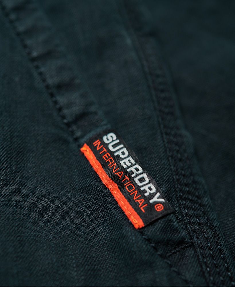 Superdry men's International Linen Chino shorts. Classic design shorts and classic chino twill fabric, but made from linen instead. Lightweight and cool to the touch, these shorts are ideal for the warmer weather when comfort is key. Featuring a zip fly fastening, five pocket design and belt loops. Completed with a logo tab on one front pocket and small logo badge above the back pocket, pair with a crisp, short sleeve shirt for a smart, yet casual look.