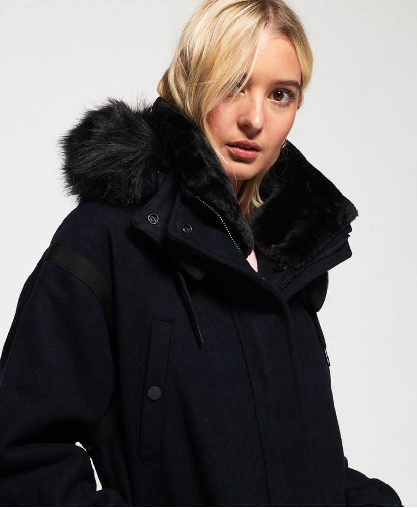 Superdry women’s Fjord Ovoid parka coat. With a wool blend fabric this premium coat is perfect for keeping warm whilst looking stylish this season and features a detachable drawstring hood with a zip and a faux fur trim which is also detachable, a super soft fleece lined collar and a single zip and popper fastening. The Fjord Ovoid parka coat features six external front pockets, four of which have popper fastenings. This coat is finished off with detailing on the seams, a metal Superdry logo badge on one of the pocket openings and a Superdry logo patch near the hem.