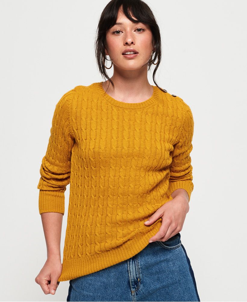 Superdry women's Croyde cable knit jumper. This soft cable knit jumper features a crew neck, button detailing at the shoulder and is completed with a small logo badge above the hem. Pair with a denim skirt and boots for an effortless, everyday outfit.