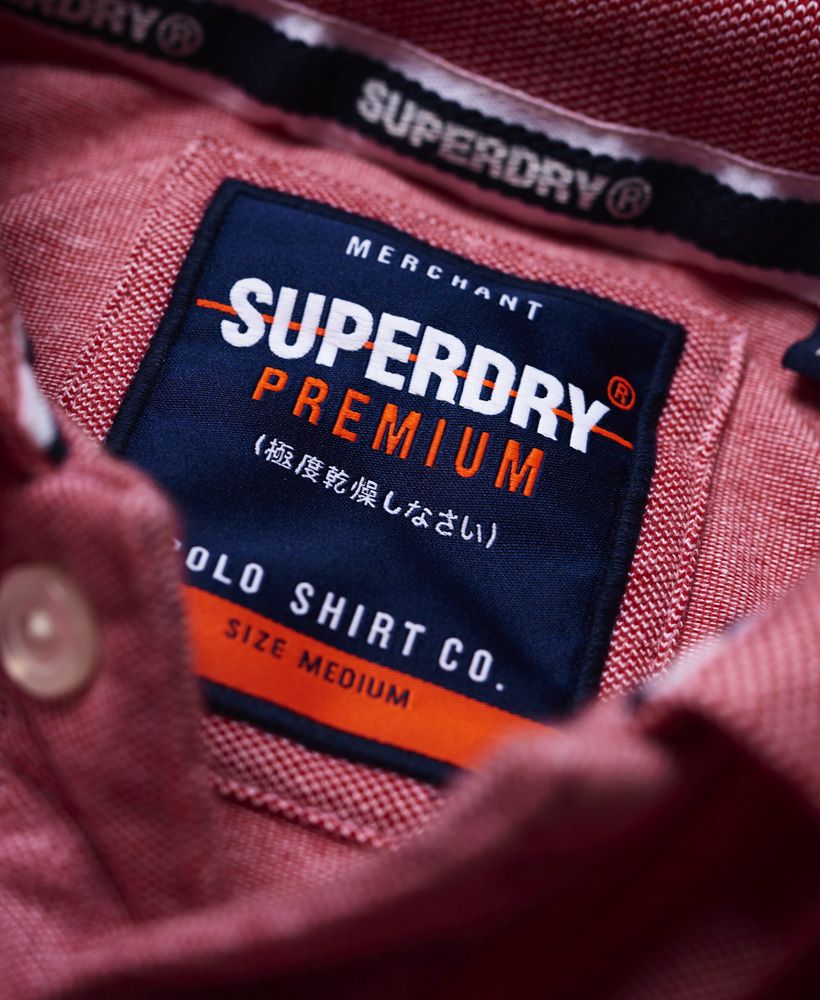 Superdry men's Poolside pique polo shirt. This classic polo features short sleeves, logo embroidery on the chest in contrast stitching and split side seams. The polo is completed with stripe detailing around the collar and cuffs and logo tabs on the sleeve and above the hem.Slim fit