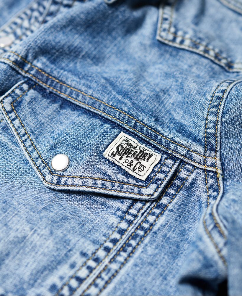 Superdry women's Western denim shirt. This long sleeved shirt features two front pockets on the chest and popper fastenings. Finished with a metal Superdry badge on one of the pockets. The Western denim shirt is effortless, why not try tying at the front for an on trend look.