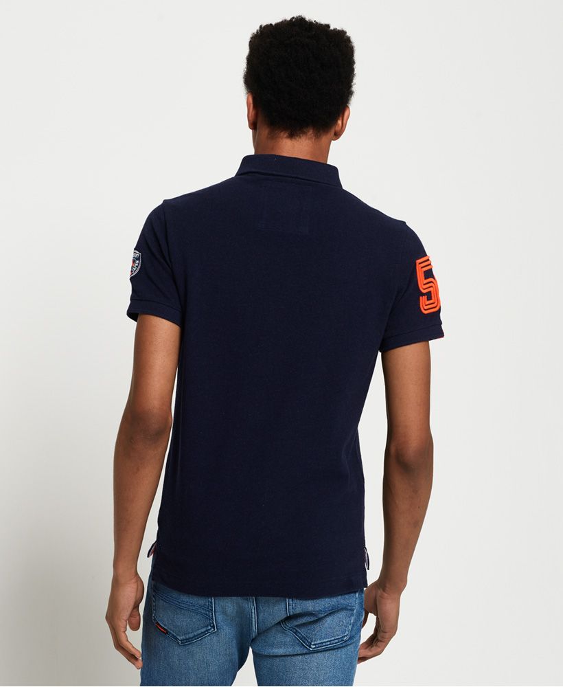 Superdry men's Superstate classic polo shirt. This polo shirt features a twin button fastening, split side seams and embroidered logo detailing on the chest. The polo also features logo graphics on the sleeves and is completed with a logo tab above the hem.Made with Organic Cotton - Made using cotton grown using organic farming methods which minimise water usage and eliminate pesticides, maximising soil health and farmer livelihoods.Slim fit