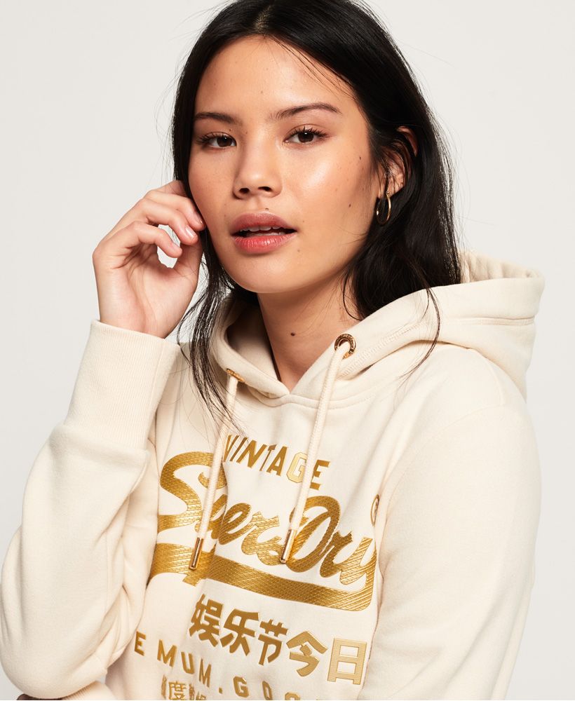 Superdry women's Vintage Logo premium luxe hoodie. A classic style overhead hoodie featuring a drawstring hood, soft lining, a large pouch pocket and ribbed cuffs and hem. Finished with a large textured Superdry logo across the front and a Superdry logo tab on the side seam.