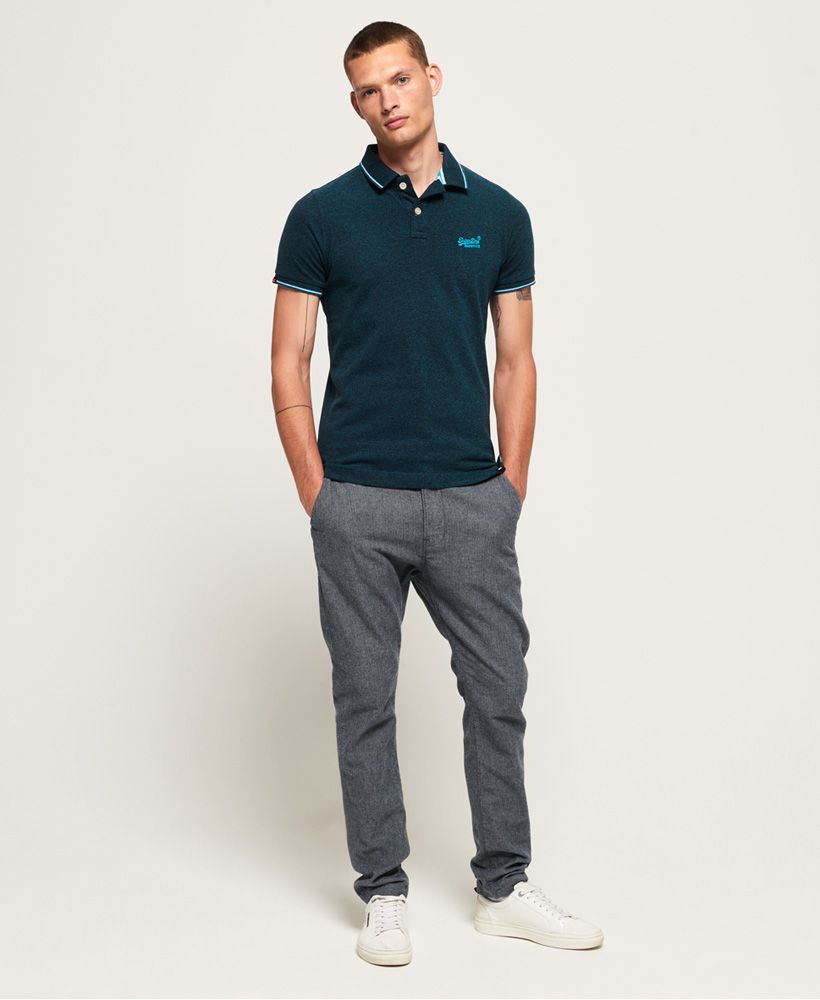 Superdry men's Poolside pique polo shirt. This classic polo features short sleeves, logo embroidery on the chest in contrast stitching and split side seams. The polo is completed with stripe detailing around the collar and cuffs and logo tabs on the sleeve and above the hem.Slim fit