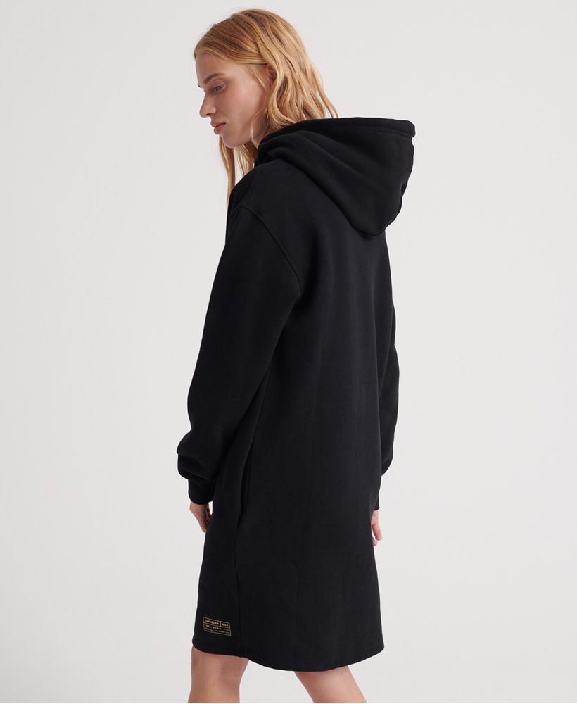 Superdry women's Oversized Scandi hooded dress. This hooded dress features a Superdry graphic across the chest, two pockets, and ribbed hem and cuffs. Completed with an adjustable drawstring hood and printed Superdry Logo on the hem.