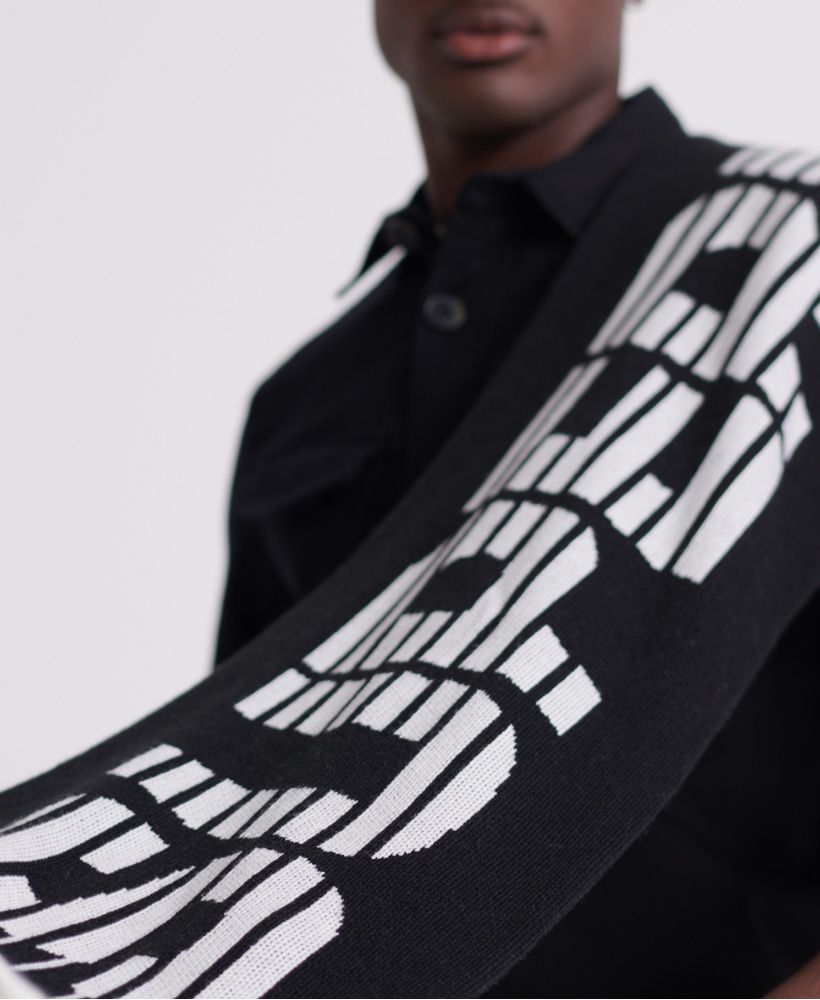 Superdry men's Mono Logo scarf. Big, bold and bound to make a statement. This scarf is must-have for cold weather dressing. Supersoft and in on-trend monochrome, the Mono Logo scarf features a striped design witht he Superdry logo knitted into the fabric. The scarf is finished with a Superdry logo patch at one end.